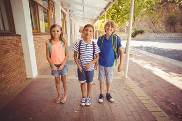 Fototapeta premium Smiling school kids standing in school corridor 
