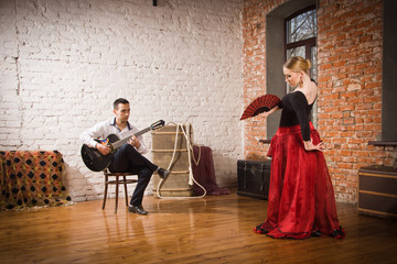 Obraz premium Young woman dancing flamenco and a man playing the guitar