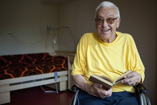 A senior man in a wheelchair flipping through a book