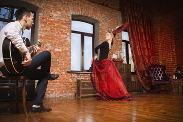 Young woman dancing flamenco and a man playing the guitar - obrazy, fototapety, plakaty