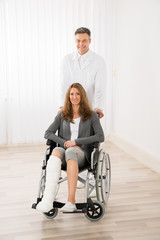 Doctor Assisting Woman On Wheelchair