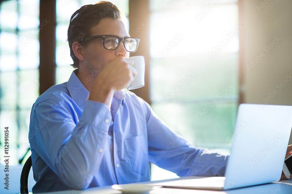 Poster Man drinking a coffee while using a laptop