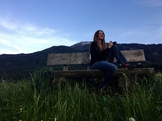 junge Frau sitzt auf Holzbank