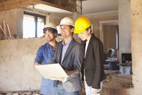 A building contractor and architects looking at a laptop at a building site
