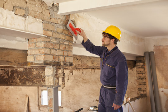 A manual worker applying plaster to a brick wall