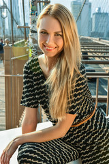 Portrait of beautiful blonde young woman wearing fashionable clothes, smiling looking at the camera. City fashion photo.