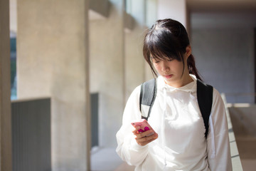 Portrait of thai student university beautiful girl using her smart phone.