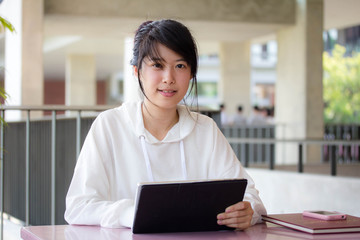 Portrait of thai student university beautiful girl using her tablet