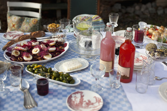 Dining table outside with crockery  and food such as olives and goat's cheese