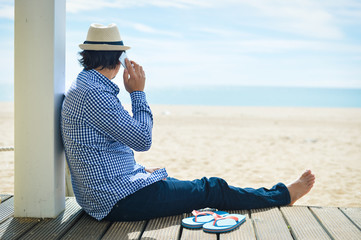 Back side view of man talking on smartphone. beach terrace sunny day background outside 