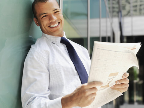Smiling businessman holding a newspaper 