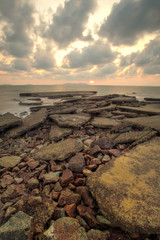 A long exposure picture of seascape sunrise with rocks in foreground