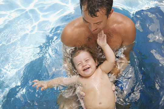 Smiling father and son playing in swimming pool
