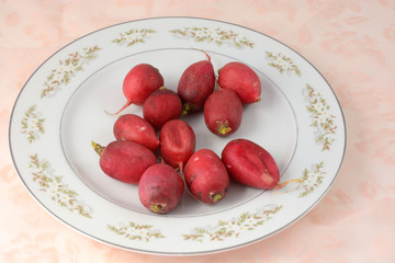 Whole raw radishes on white plate