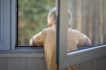 Rear view of a boy looking out a window