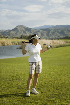 A golfer standing with golf clubs across her shoulders, Palm Springs, California, USA