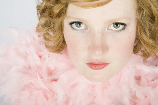Portrait of a young woman wearing a pink feather boa