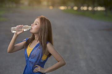 Beautiful Woman drinks Water after Fitness exercise