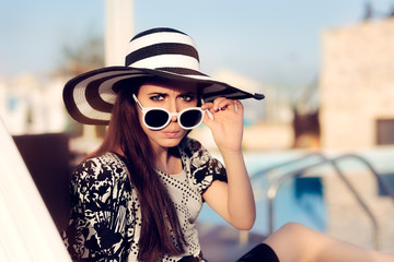 Surprised  Girl With Sunglasses and Hat  Sitting on Sun Chair