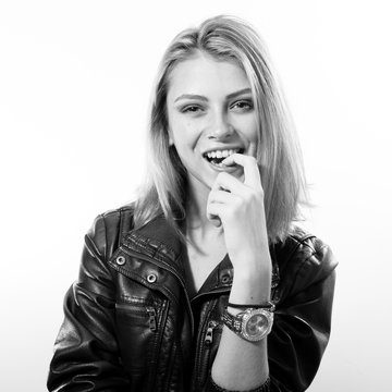fashion rock star: black and white portrait of sexy young blonde woman in leather jacket posing happy smiling over light copy space background