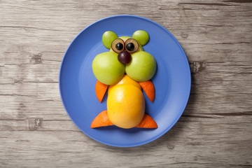 Funny hamster made of fruits on plate and wooden background