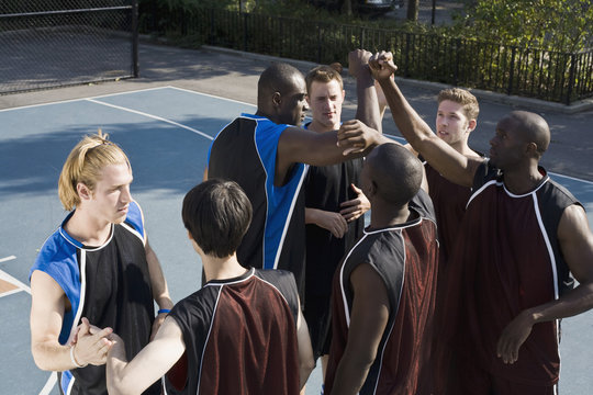 Two teams of basketball players shaking hands
