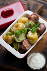 Three colored meat dumplings with green basil and sour cream