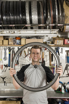 A man holding a bicycle wheel in a workshop