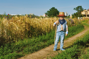 Naklejka na ściany i meble Little boy dressed in Western style in the field