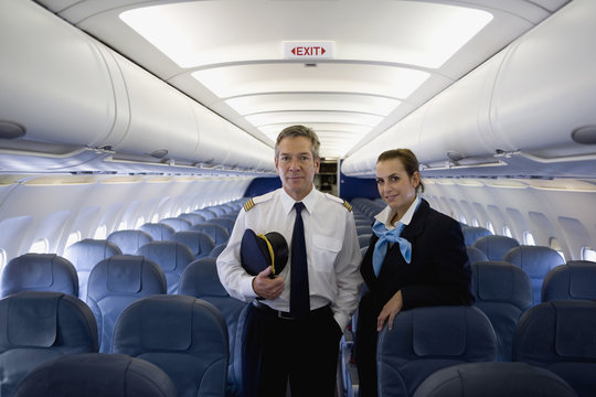 A Pilot And A Flight Attendant Standing In The Cabin Of A Plane