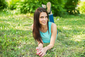 Obraz premium Beautiful woman relaxing outdoors on grass looking happy and smiling.