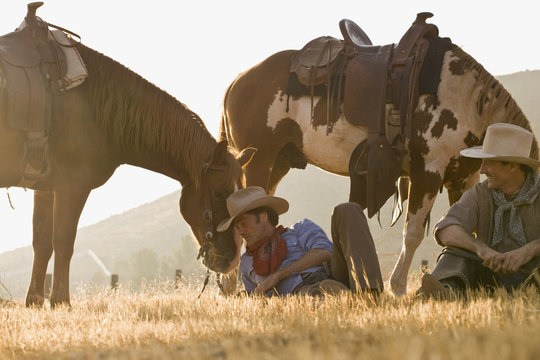 Two cowboys resting with their horses