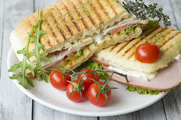 Sandwich with ham and tomatoes on wood background