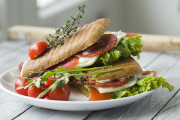 Sandwich with ham and tomatoes on wood background