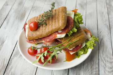 Sandwich with ham and tomatoes on wood background