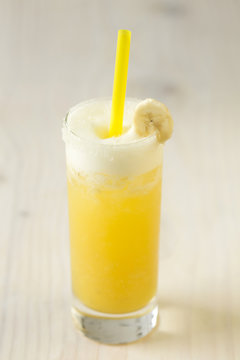 Yellow lemonade with banana in a glass on table close-up