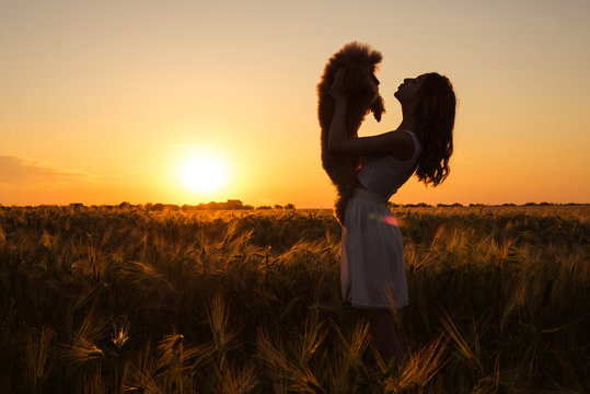 Beautiful  girl  with his dog on the field in sun light. 