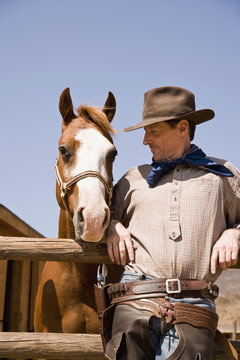 Portrait of cowboy standing next to a horse