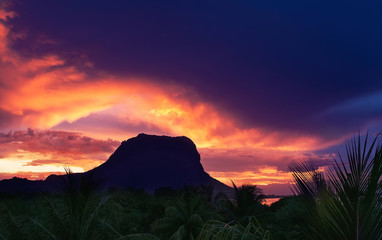 Berg Le Morne Brabant auf einem schönen Sonnenuntergang Himmelshintergrund und Palmen im Vordergrund. Le Morne Brabant, Insel Mauritius. Blick von la Gaulette.