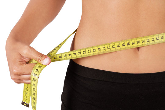 Foto de Mujer midiendose la cintura con un metro sobre un fondo blanco.  Vista de frente y de cerca. Concepto: Salud do Stock