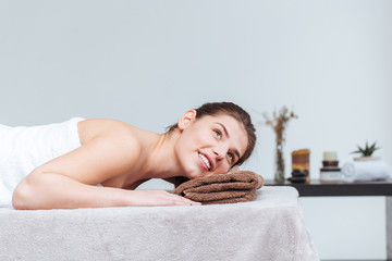 Obraz na płótnie Canvas Happy pretty young woman smiling and lying in spa salon