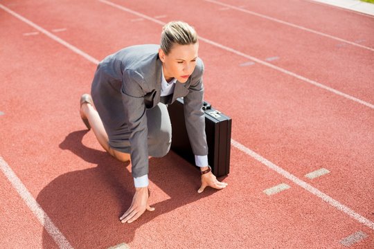 Businesswoman with briefcase in ready to run position - Powered by Adobe