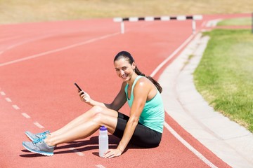 Portrait of happy female athlete using mobile phone