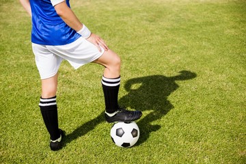 Female football player standing with her feet on ball