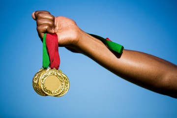 Naklejka na ściany i meble Athlete hand showing his gold medals