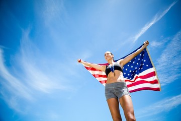 Obraz na płótnie Canvas Happy female athlete holding up american flag 