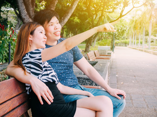 Asian couple sitting on the bench in the park together