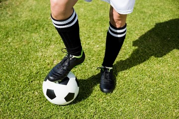 Obraz premium Female football player standing with her feet on ball