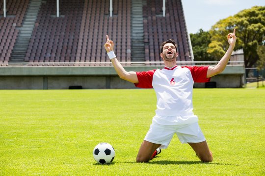 Excited Football Player Kneeling In Stadium