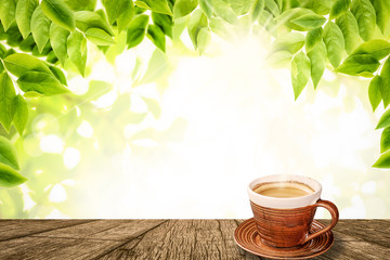 Good morning Coffee. Cup of coffee on wooden table and natural green leaves background.